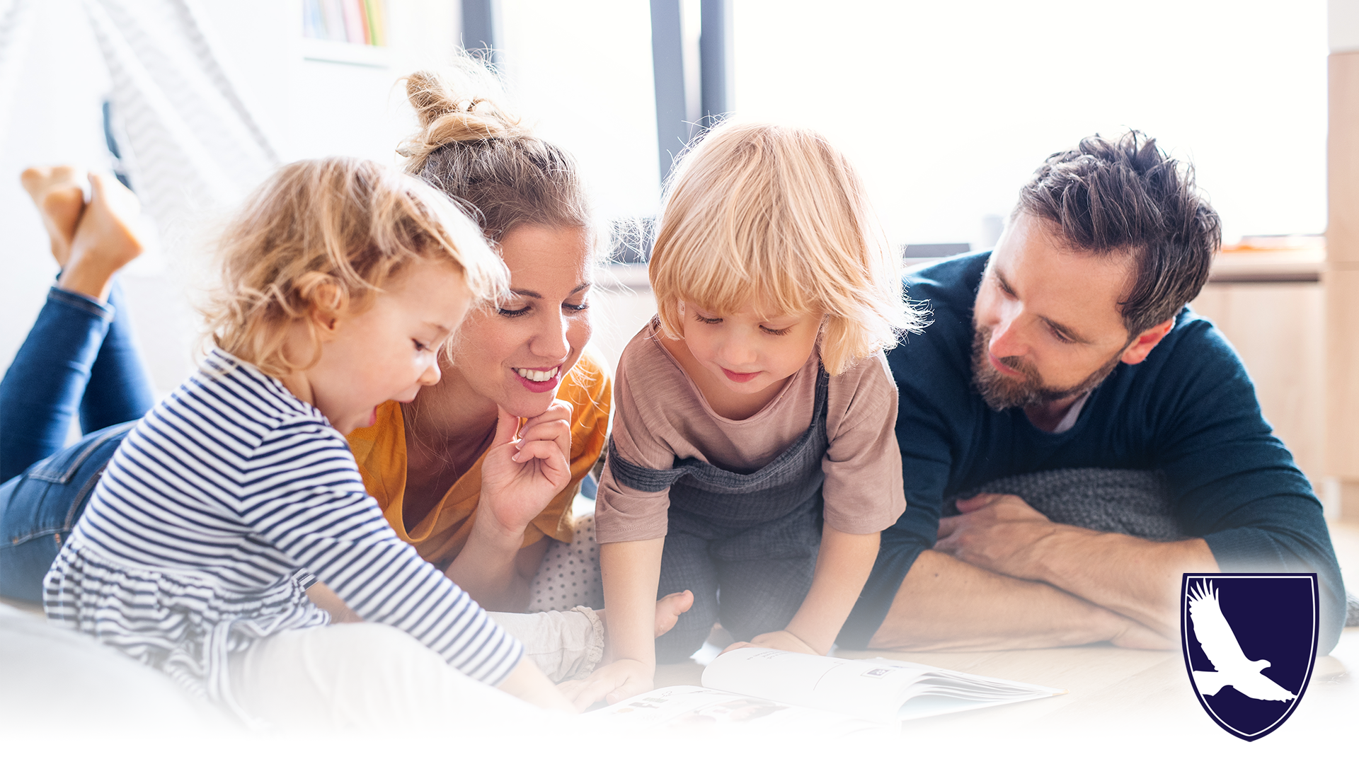 Image of two parents and their two children together reading a book